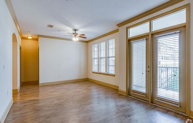 an empty living room with windows and a ceiling fan