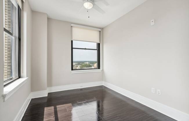 an empty bedroom with a window and a ceiling fan