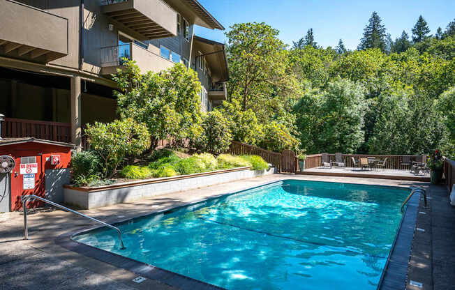 A swimming pool surrounded by trees and apartment buildings.