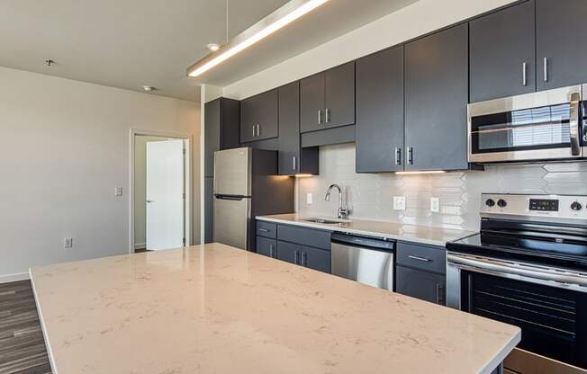 an empty kitchen with black cabinets and a white counter top