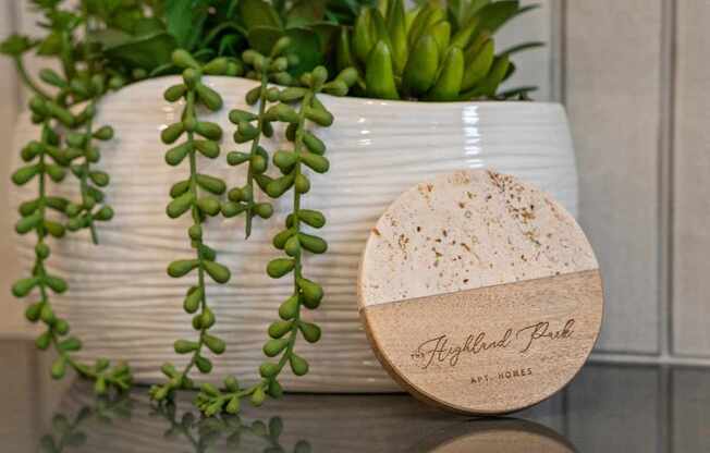 A white ceramic pot with a plant and a wooden box with the text