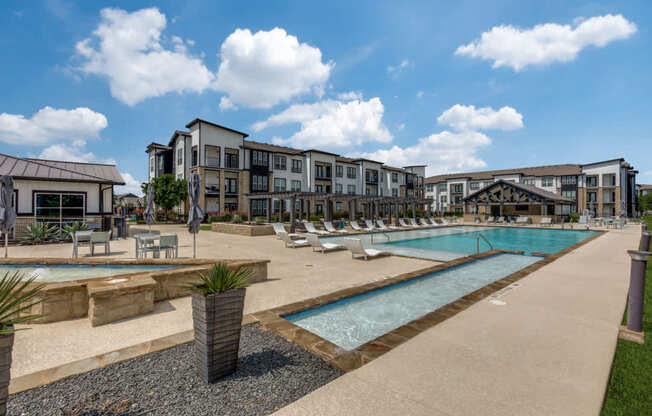 A large outdoor swimming pool surrounded by lounge chairs and umbrellas.