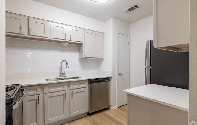 A kitchen with white cabinets and a black refrigerator.