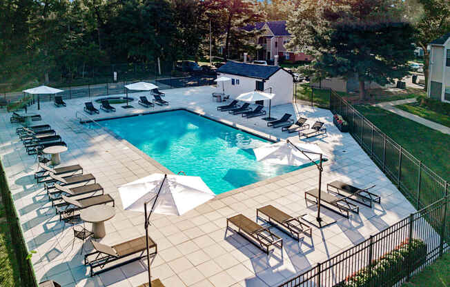 A large outdoor swimming pool surrounded by sun loungers and umbrellas.