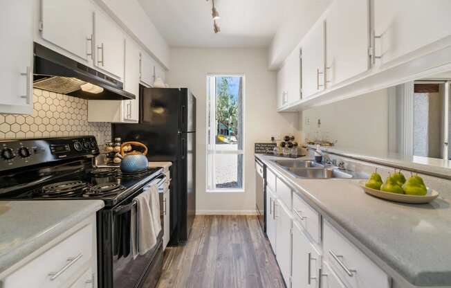 a kitchen with white cabinets and black appliances and a window