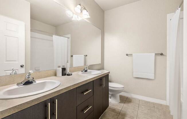 A bathroom with a white sink, toilet, and a mirror.