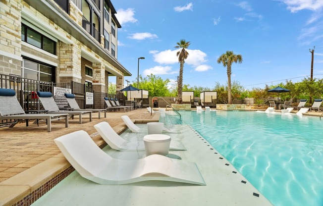 A pool with a white bench and a building behind it.