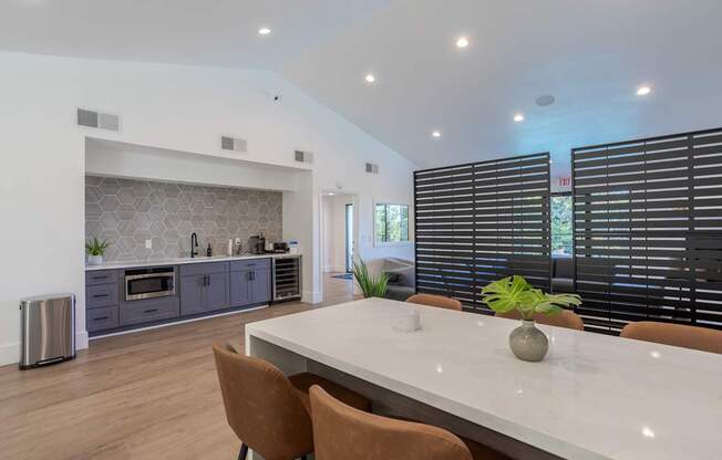 A modern kitchen with a white dining table and brown chairs.