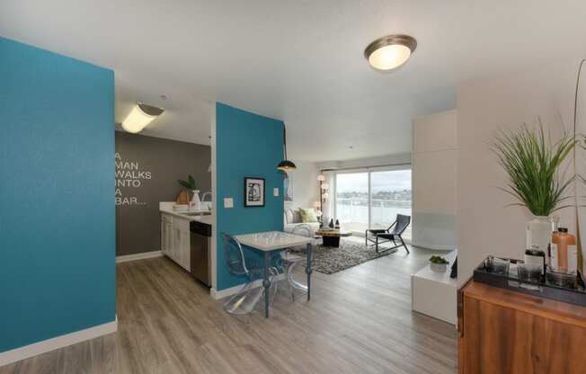 Kitchen and View of Living Room with Blue Walls, Hardwood Inspired Floor and Table with See Through Chairs