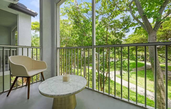 a balcony with a table and a chair and a view of trees