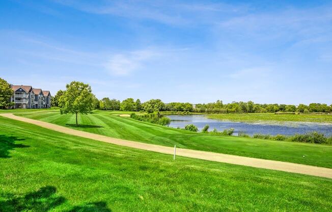 a golf course with a body of water and houses in the background