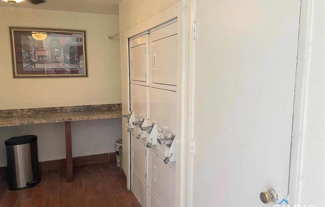 A room with a white door, a brown table, and a framed picture on the wall.