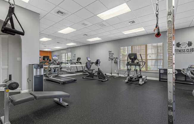 a gym with cardio equipment and weights on the floor