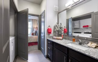 a bathroom with a sink and a mirror and a door to a bedroom at North Creek, Hutto, TX