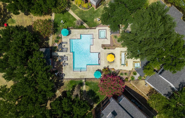 an aerial view of a backyard with a large swimming pool with blue and yellow umbrellas