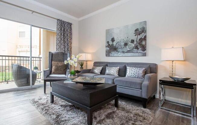 A living room with a grey couch, a black coffee table, and a large abstract painting on the wall.