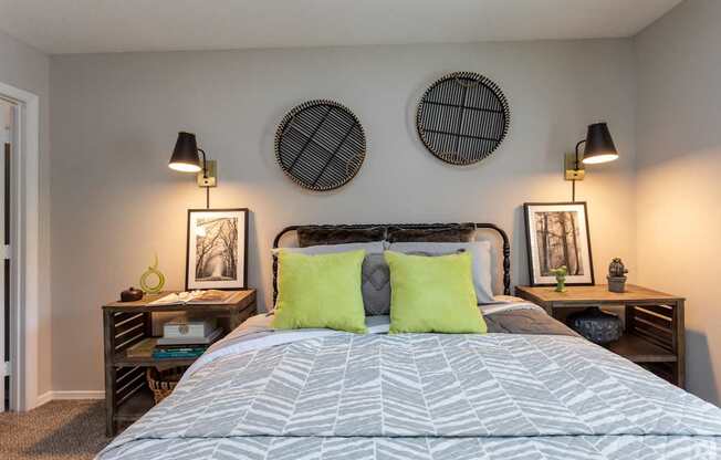 a bedroom with a bed with green pillows and two nightstands with lamps