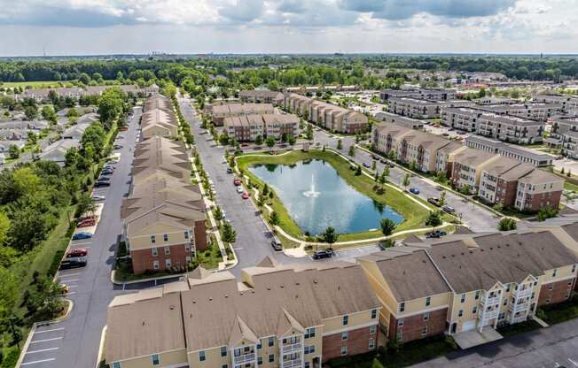 an aerial view of an apartment community with a pond in the middle