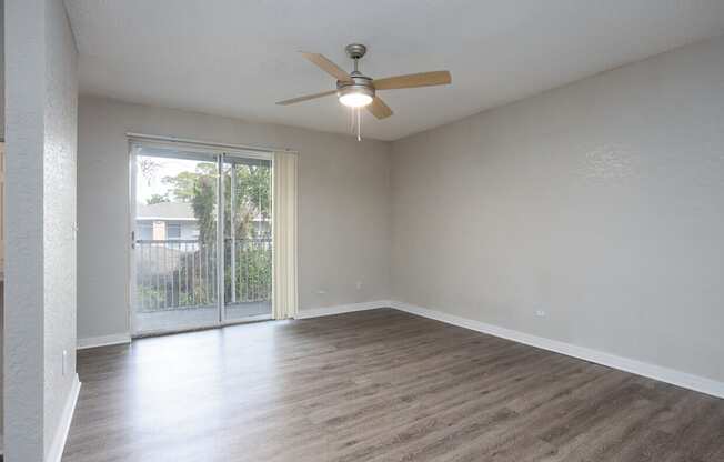 A room with a ceiling fan and sliding glass doors.