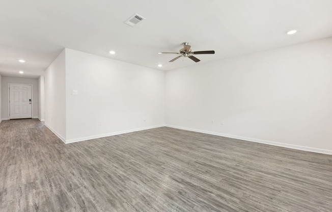 an empty living room with white walls and a ceiling fan