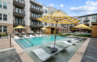 a swimming pool with yellow umbrellas and white lounge chairs