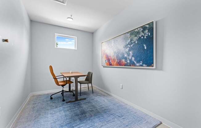 A room with a table and chairs and a painting on the wall.