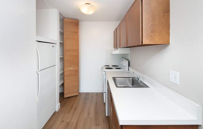 a kitchen with white countertops and wood flooring
