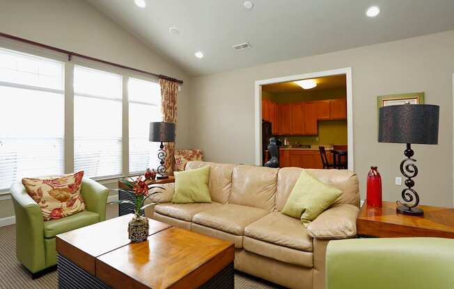 A living room with a tan couch, green armchair, and a wooden coffee table.