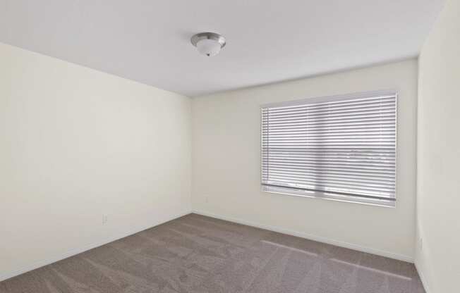 a bedroom with a large window and white walls