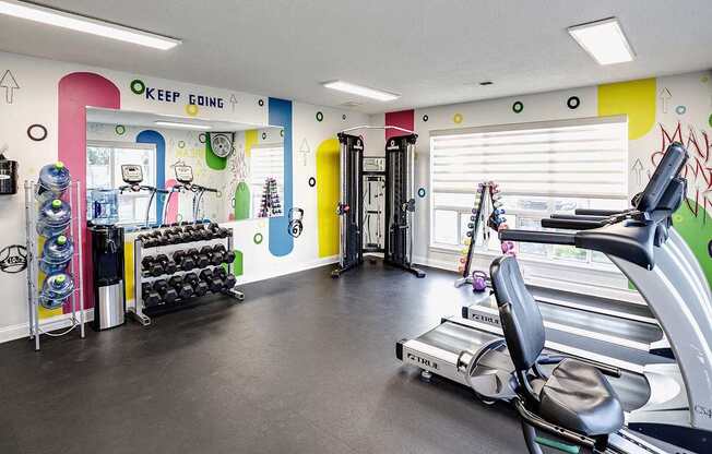 A gym with a variety of equipment including weights, a treadmill, and a stationary bike.