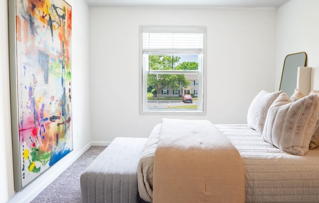 a bedroom with a large painting on the wall and a bed with a blanket and pillows