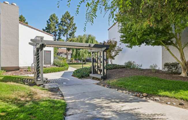 A white building with a black gate and a tree in front.