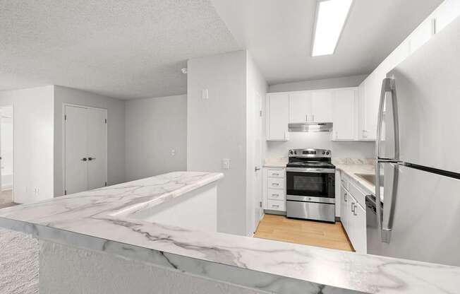 A modern kitchen with a marble countertop and stainless steel appliances.