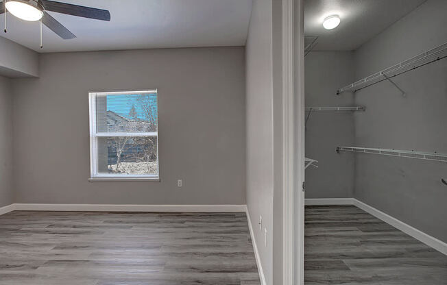 an empty room with a window and a ceiling fan