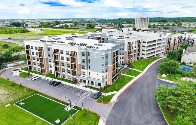 A large apartment complex with a green lawn and a playground.