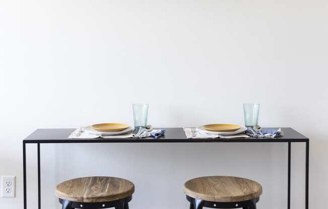 a kitchen with two stools and a table with a shelf on the wall at Analog PDX Apartments, Portland