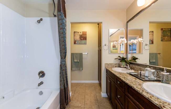A bathroom with a white tub and brown countertops.