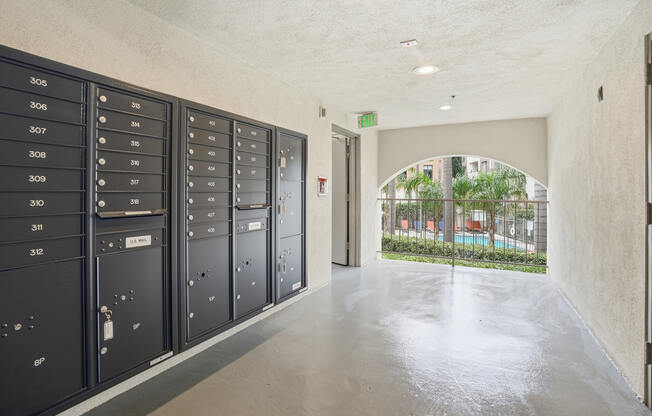 A hallway with a row of lockers on the left and a doorway leading to a balcony on the right.