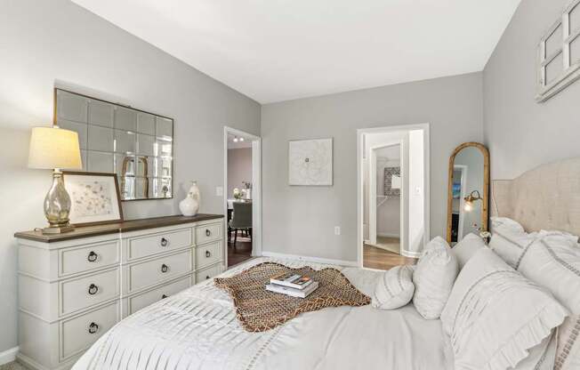 A bedroom with a large bed, a dresser, and a mirror.