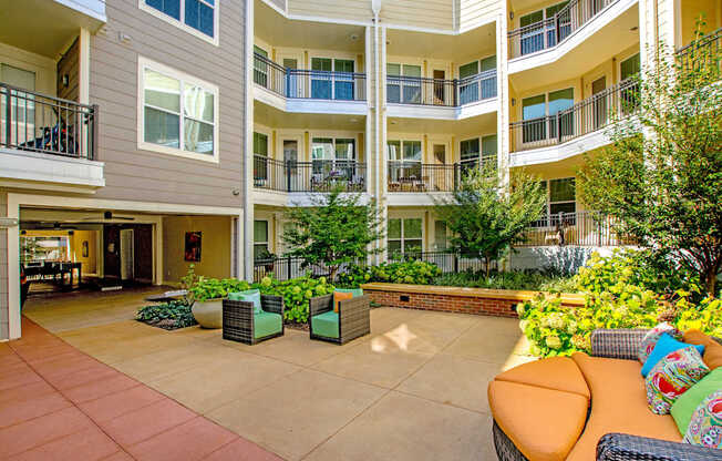 A courtyard with a couch and chairs surrounded by apartment buildings.