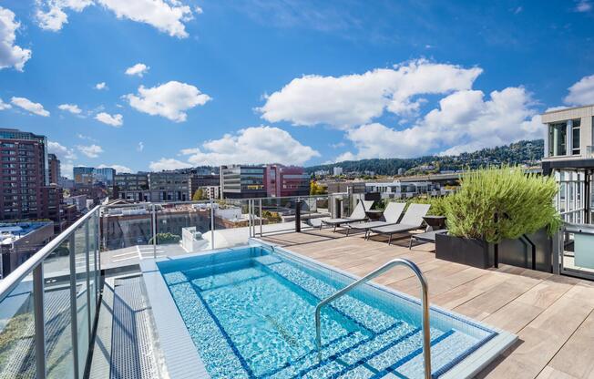 A rooftop pool at Modera Pearl with panoramic city views, sun loungers, and open decking designed for refreshing daytime breaks above Portland.