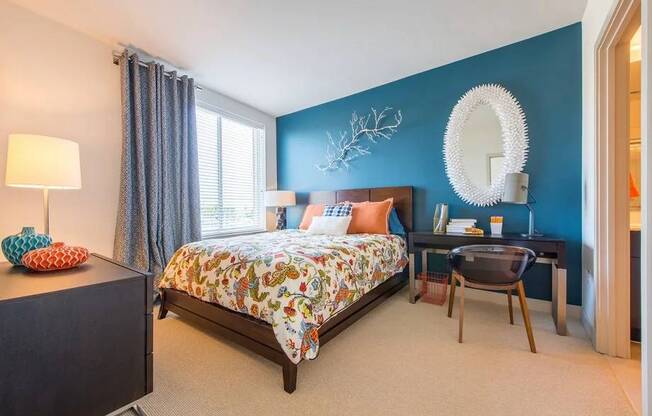 A bedroom with a bed, a desk, and a chair.