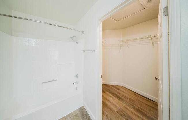 A white bathroom with a walk-in shower and a wooden floor.