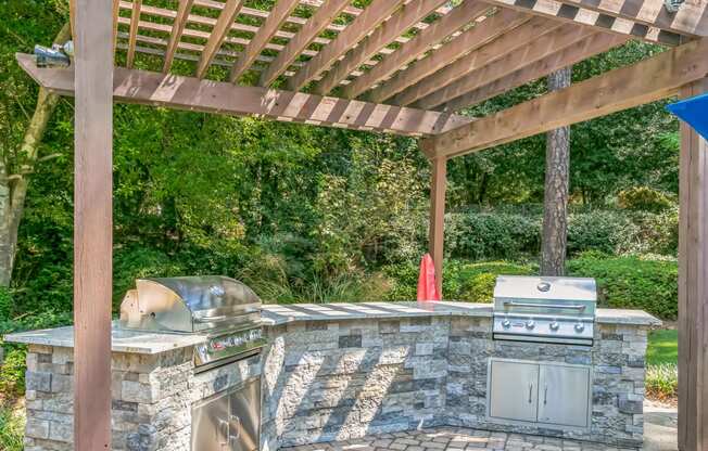 an outdoor kitchen with a grill and a pergola