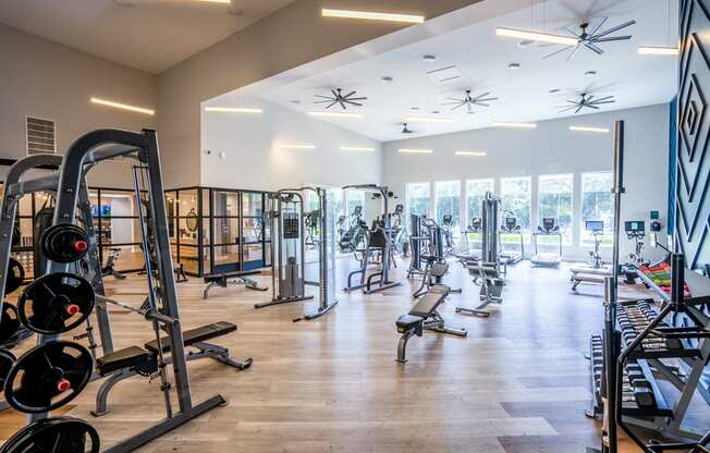 a large fitness room with cardio equipment and glass windows