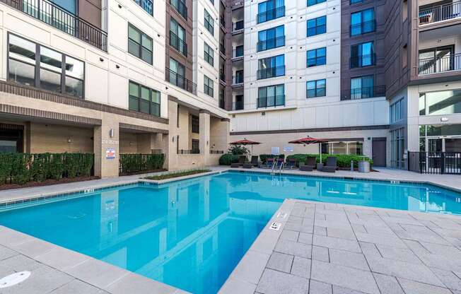 A large swimming pool in front of apartment buildings.