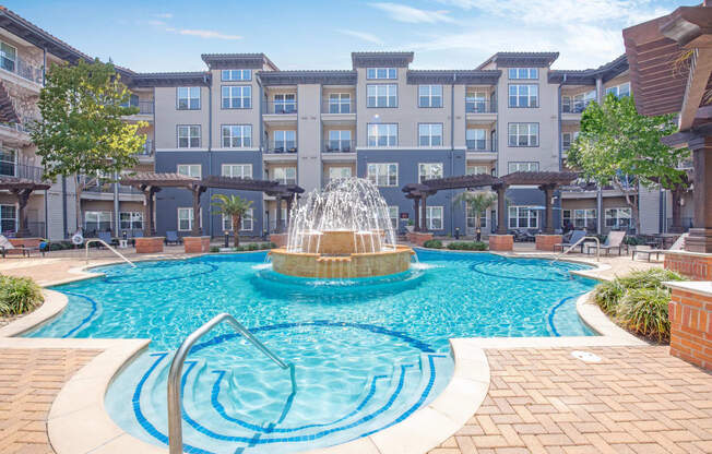 a swimming pool with a fountain in front of an apartment building