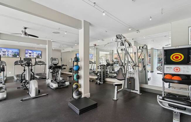A gym with a variety of exercise equipment including treadmills, stationary bikes, and weight machines.