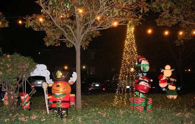 A Christmas tree is lit up at night with a nutcracker in front of it.