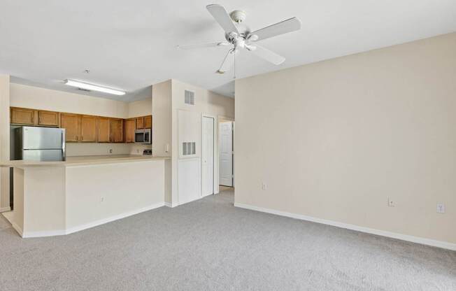 A spacious room with a ceiling fan and a kitchenette.